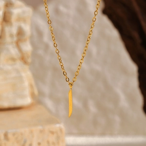 Gros plan d'un collier en acier inoxydable doré 18 carats avec pendentif lettre arabe Alif