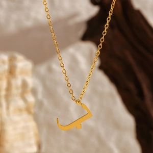 Vue macro détaillée d'un pendentif lettre arabe en or 18 carats sur une chaîne en acier