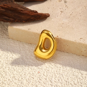 Polished gold organic bean pendant displayed on stone and wood background