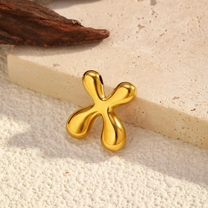 Polished gold abstract cross pendant on stone texture showing high-shine mirror finish