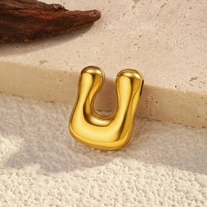 Macro detail of a high-polished golden U-shaped pendant on a textured stone base
