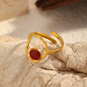 Gros plan d'une bague dorée vintage avec texture martelée et pierre rouge