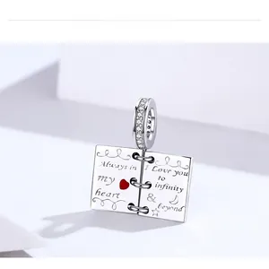 Macro detail of S925 silver open book charm with red heart and 'Always in my heart' text