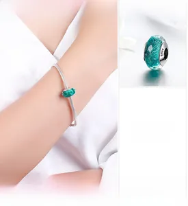 Macro detail of S925 sterling silver snake chain bracelet with green faceted glass bead