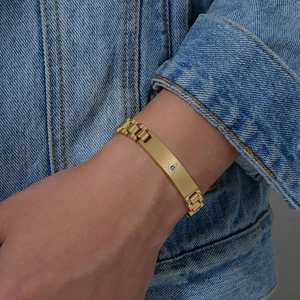 Dettaglio del bracciale massonico in acciaio dorato su una manica di jeans blu