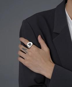 Detail of silver signet ring with lion crest worn by a model in a grey suit