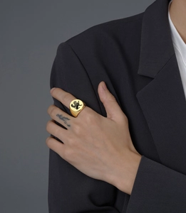 Macro detail of a gold signet ring featuring an engraved black lion crest on a round face