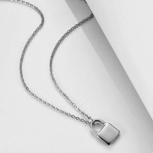 Détail d'une chaîne double en argent minimaliste avec un pendentif cadenas rectangulaire poli