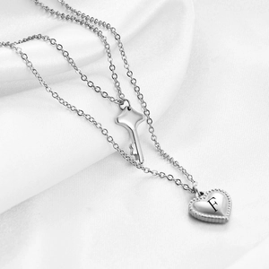 Dettaglio collana doppia in argento con ciondoli a chiave e cuore con lettera F