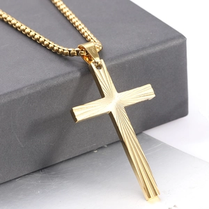 Macro shot of 50mm gold cross pendant with radial stripe texture on stainless steel