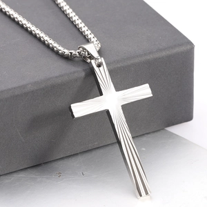 Detail of cross pendant with radial texture on a box chain over a jewelry gift box