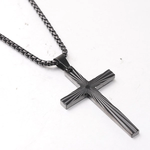 Macro view of black stainless steel cross pendant with textured radial stripes and box chain