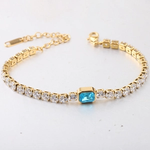 Macro-opname van gouden tennisarmband met blauwe rechthoekige steen en witte zirkonia