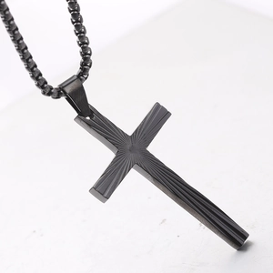 Close-up of matte black stainless steel cross pendant with detailed radial engraved texture