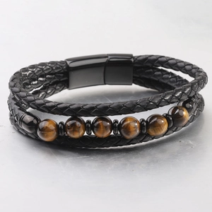 Detalle de pulsera multicapa de cuero trenzado con cuentas ojo de tigre y cierre magnético