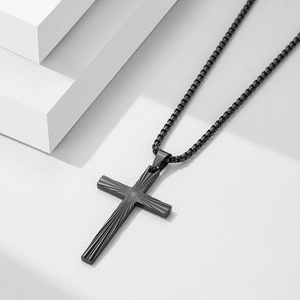 Close-up of matte black 50mm cross pendant showing radial texture and box chain