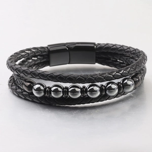 Vista macro de la pulsera multicapa de cuero trenzado negro con cuentas grises y cierre imán