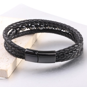 Detalle de una pulsera multicapa de cuero trenzado negro con cuentas y cierre magnético