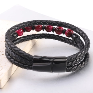 Detalle macro de pulsera multicapa de cuero trenzado con cuentas rojas y cierre de metal negro