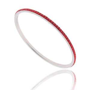 Detail view of silver stainless steel bangle with a row of inlaid red crystals and reflection