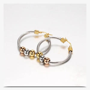 Detail van gedraaide kabel oorbellen met gouden, zilveren en roségouden kralen