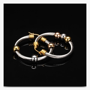 Detail van driekleurige kralen kabel oorbellen in goud, zilver en roségoud finish
