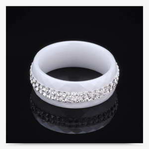 Macro detail of white ceramic ring with dual-row crystal inlay and diamond cut texture