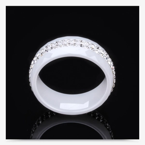 Macro detail of white ceramic ring with double row of rhinestones and faceted edges