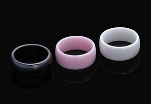 Polished 8mm ceramic rings in black, pink, and white on reflective background