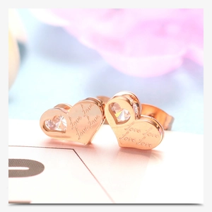 Macro-opname van roségouden hartoorbellen met Love-gravure en hartvormige zirkonia
