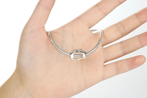 Dettaglio del bracciale a catena serpente con ciondolo mani che tengono un cuore