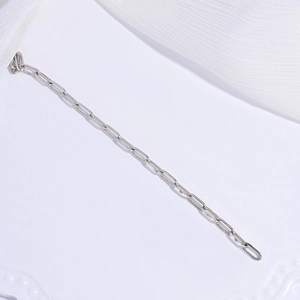 Detail of silver S925 sterling silver paperclip chain links on elegant white silk fabric