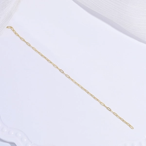 Detailed close-up of a shiny gold paperclip chain link over a white textured background
