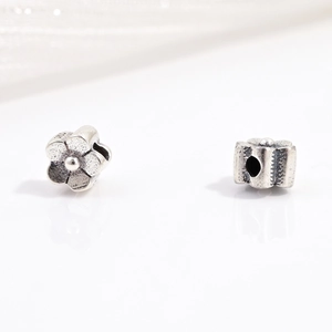 Macro detail of S925 sterling silver flower beads with oxidized vintage floral patterns