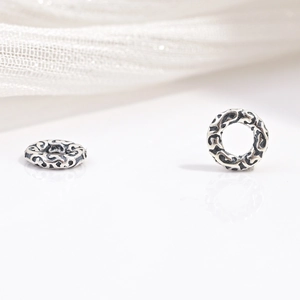 Macro view of vintage S925 sterling silver faceted gear beads with floral engravings