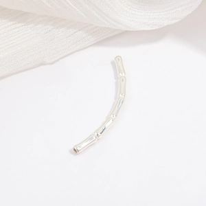 Macro detail of a polished S925 sterling silver bamboo style curved tube bead for DIY jewelry
