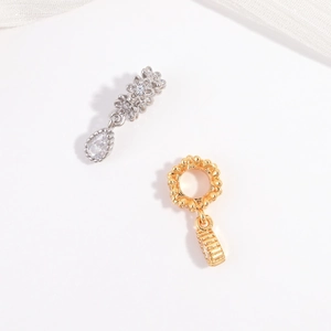 Macro shot of silver flower charm with zircon drop and gold beaded ring jewelry component