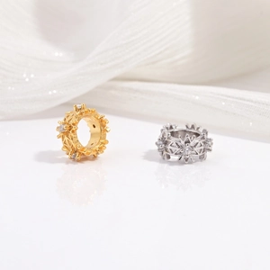 Detailed view of gold and silver snowflake charm beads with sparkling cubic zirconia