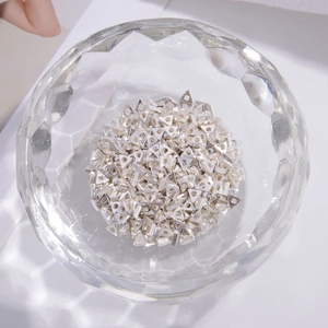 Macro shot of silver geometric triangle spacer beads for DIY jewelry making in a glass bowl