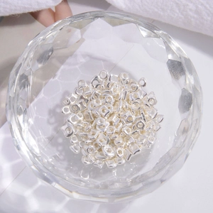 Macro shot of silver S925 cube spacer beads for DIY jewelry making in a glass bowl