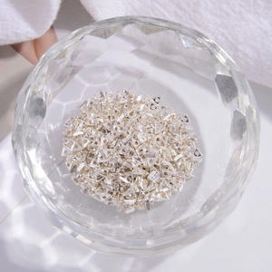 Close-up of S925 sterling silver hollow triangle spacer beads in a glass bowl