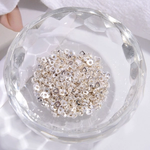 Close-up of heart-shaped S925 sterling silver beads for DIY jewelry making in a glass bowl