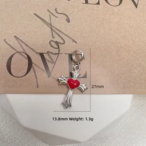 Macro shot of silver cross pendant with red enamel heart center on neutral background