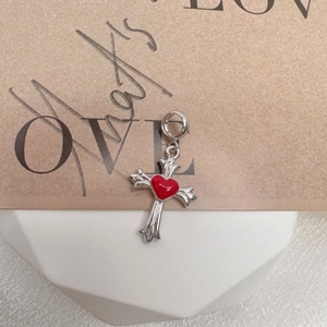 Macro shot of silver S925 cross pendant with a red enamel heart on a gift background