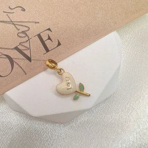 Detail showing S925 silver heart pendant with white enamel, I U letters and green leaves