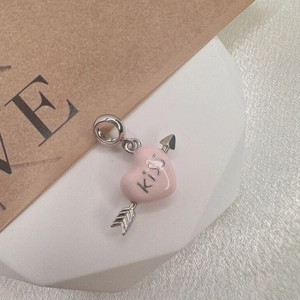 Macro detail of S925 silver Cupid arrow charm with pink enamel heart and Kiss engraving