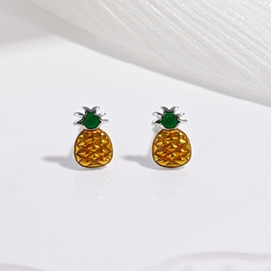 Détail de boucles d'oreilles ananas jaunes en émail vert sur un support miroir blanc