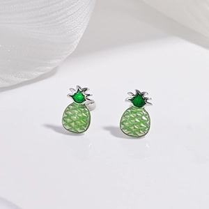 Gros plan de boucles d'oreilles ananas avec émail vert et détails en métal argenté