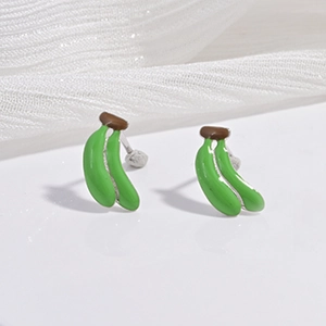 Détails de boucles d'oreilles bananes miniatures en émail posées sur un ruban de soie blanc