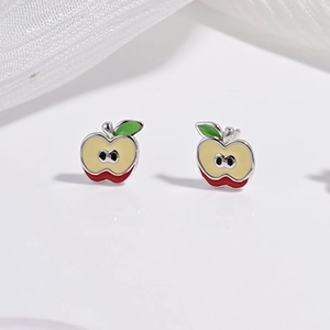 Gros plan de boucles d'oreilles pomme en argent avec émail coloré sur fond blanc poli